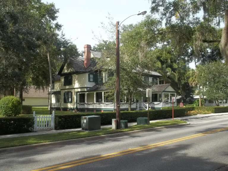 Una casa de madera de dos pisos con porche que la rodea, bajo robles, en Interlachen Avenue, Winter Park